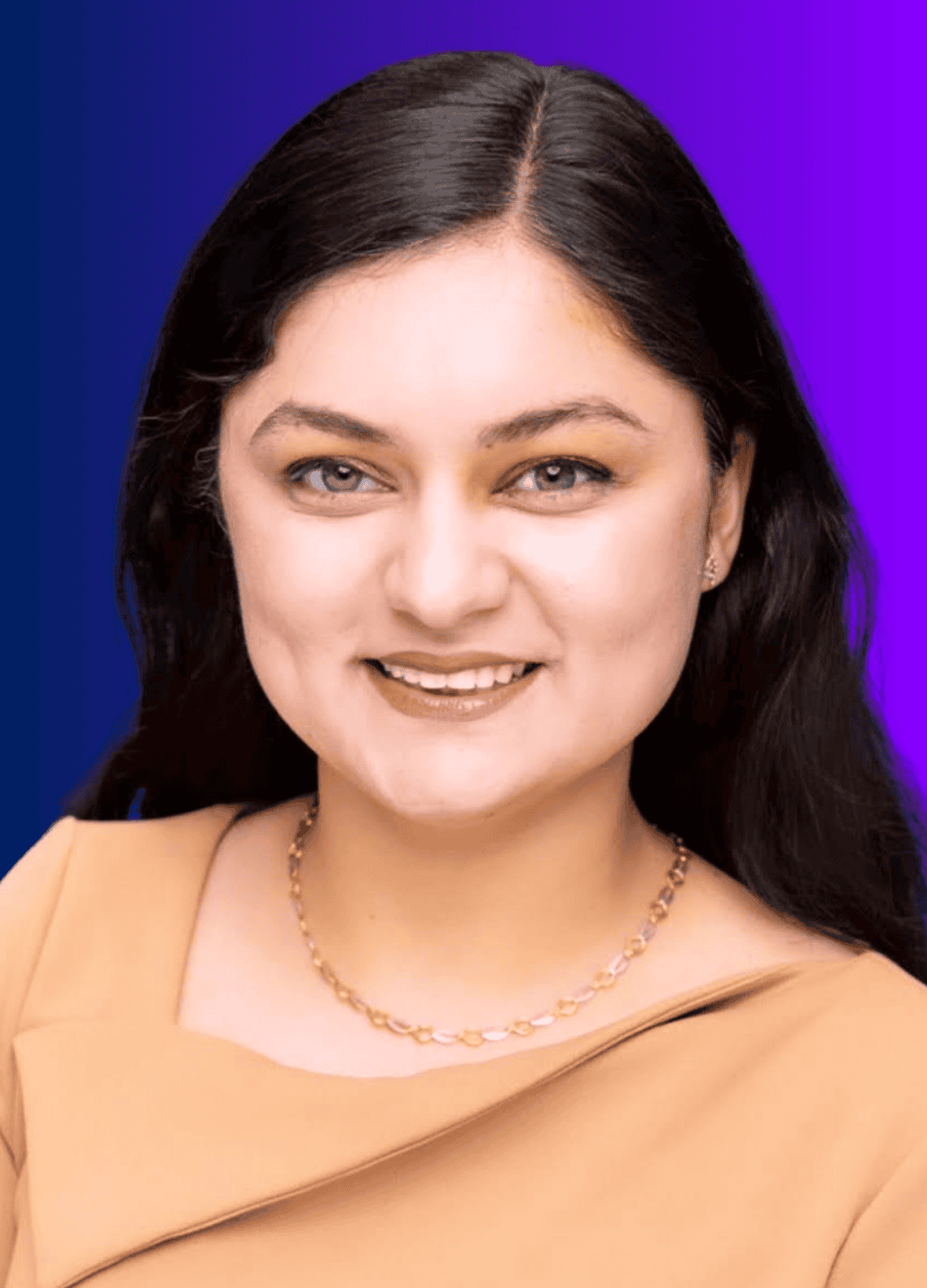 Headshot of a woman smiling, with long dark hair, wearing a tan top and a gold necklace, set against a blue-to-purple gradient background. The article title “Fractional CAIOs Explained: The Executives That Make AI Work” is associated with this image.