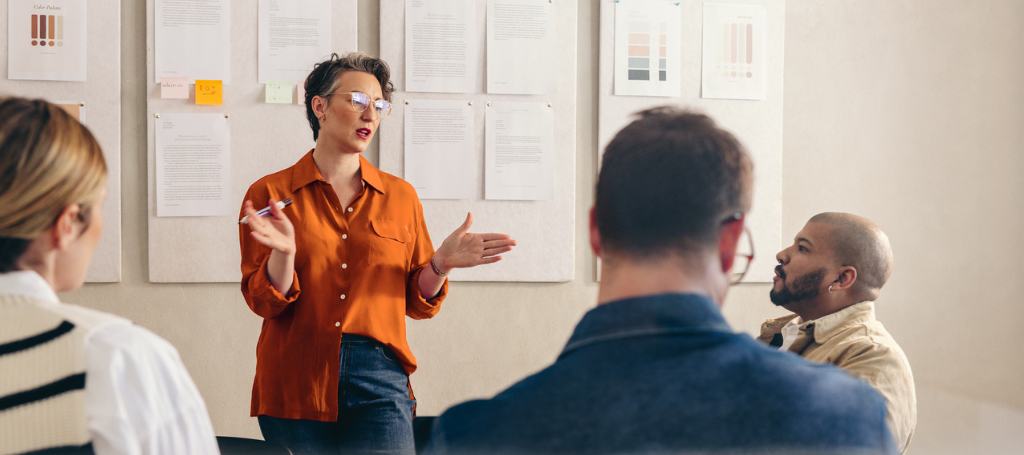 Four employees in conference room discussing strategic demand management