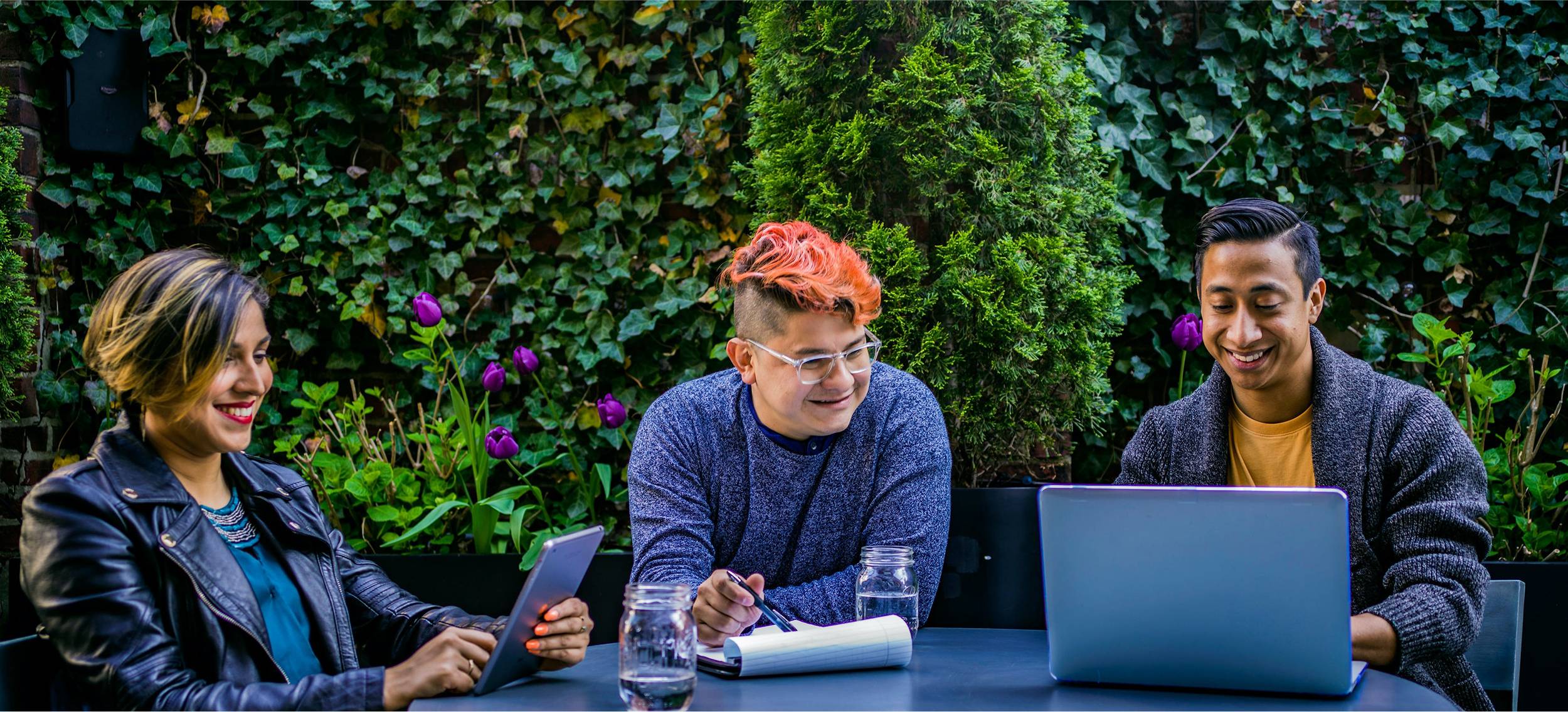 Group of three temporary staffing employees sitting outside, looking at laptop for diversity, equity, & inclusion meeting