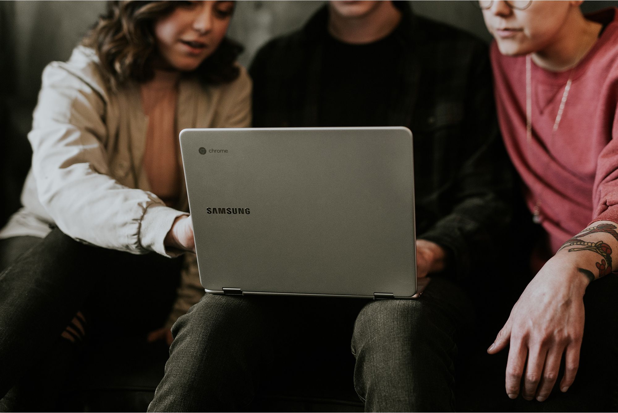 Three professionals looking at laptop researching tech staffing solutions