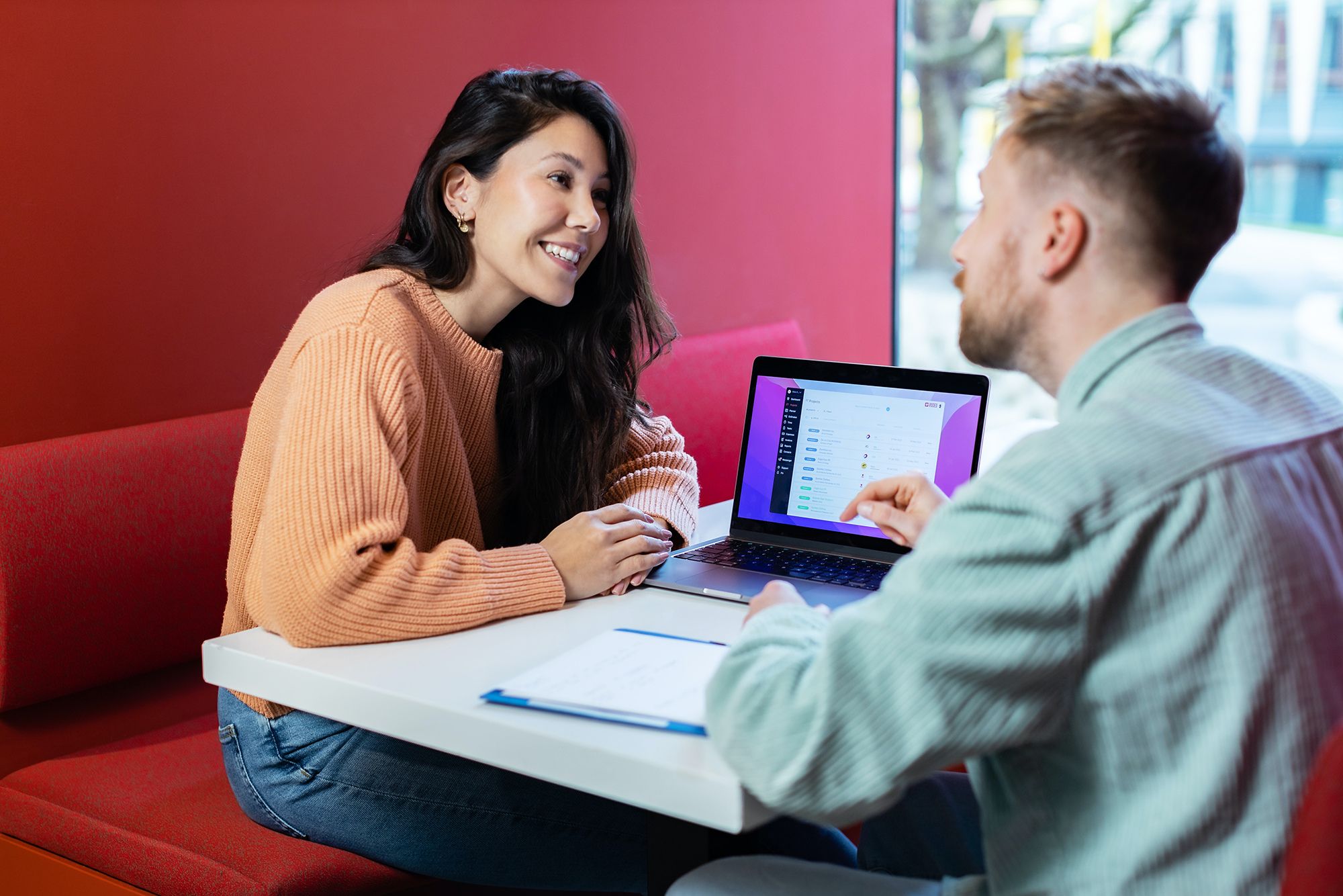 A smiling female staffing employee sitting across from a male recruiter discussing how to refer-a-friend and referral program for Onward Search