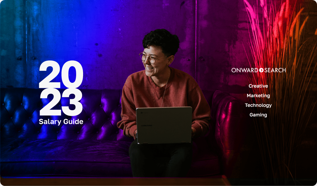 Creative professional sitting on couch with laptop looking at Onward Search 2023 Salary Guide