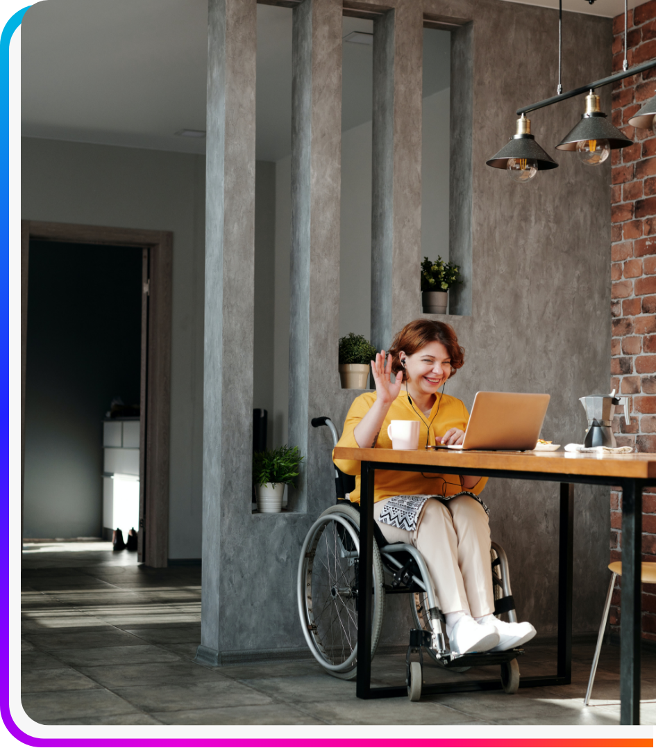 Woman staffing employee in wheelchair sitting at desk, waving at talent solutions video call on laptop