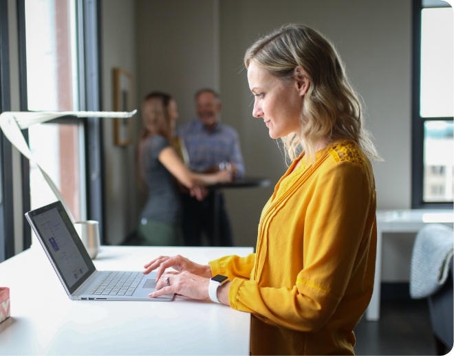 Young woman technology professional in yellow blouse researching Onward Search's talent benefits