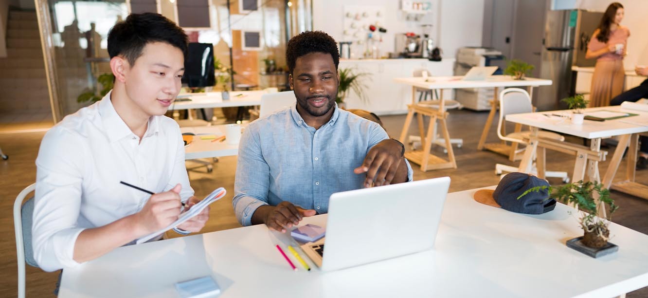 Two creative professionals sitting at desk looking at creative jobs in Chicago on laptop