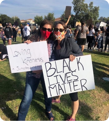 Two women Onward Search staffing employees outside holding up hand-written signs