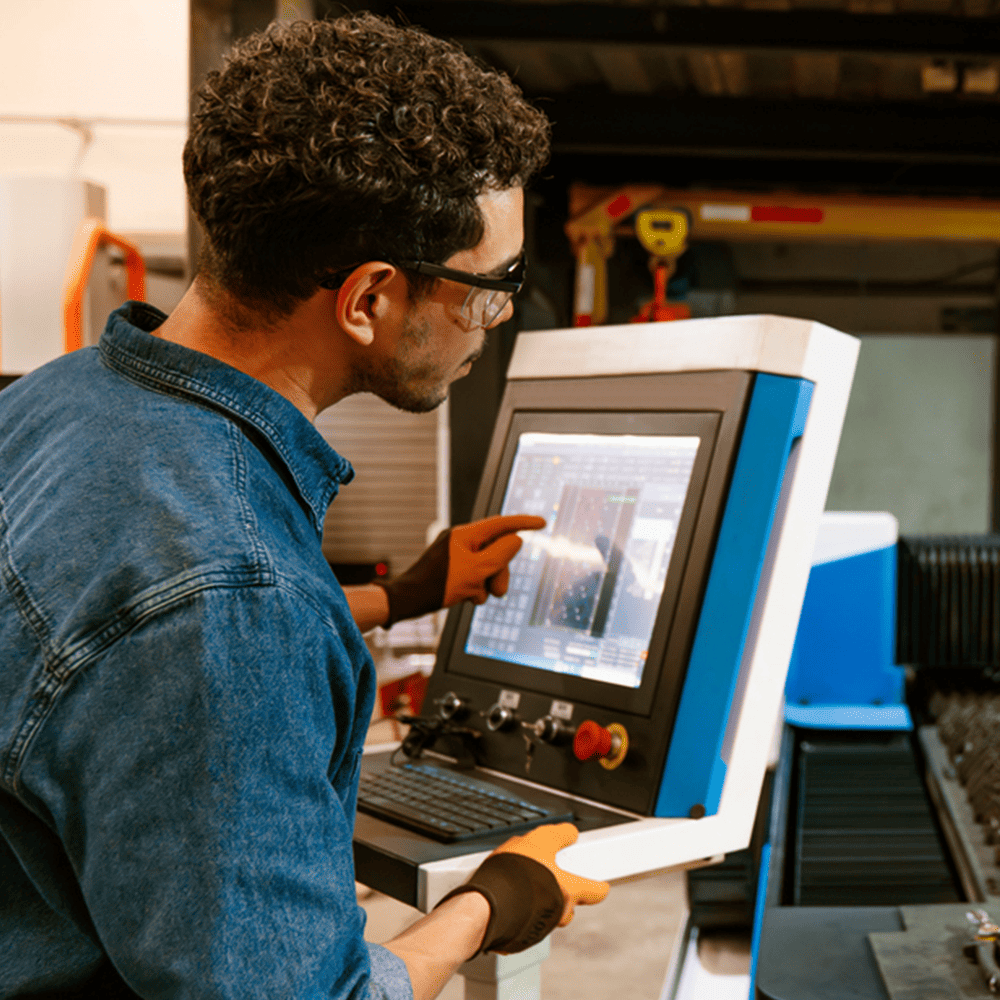 A skilled engineer operates advanced manufacturing equipment, reviewing precision settings on a digital control panel in a modern industrial workspace. The scene highlights skilled technical expertise, innovation, and problem-solving in an engineering environment.